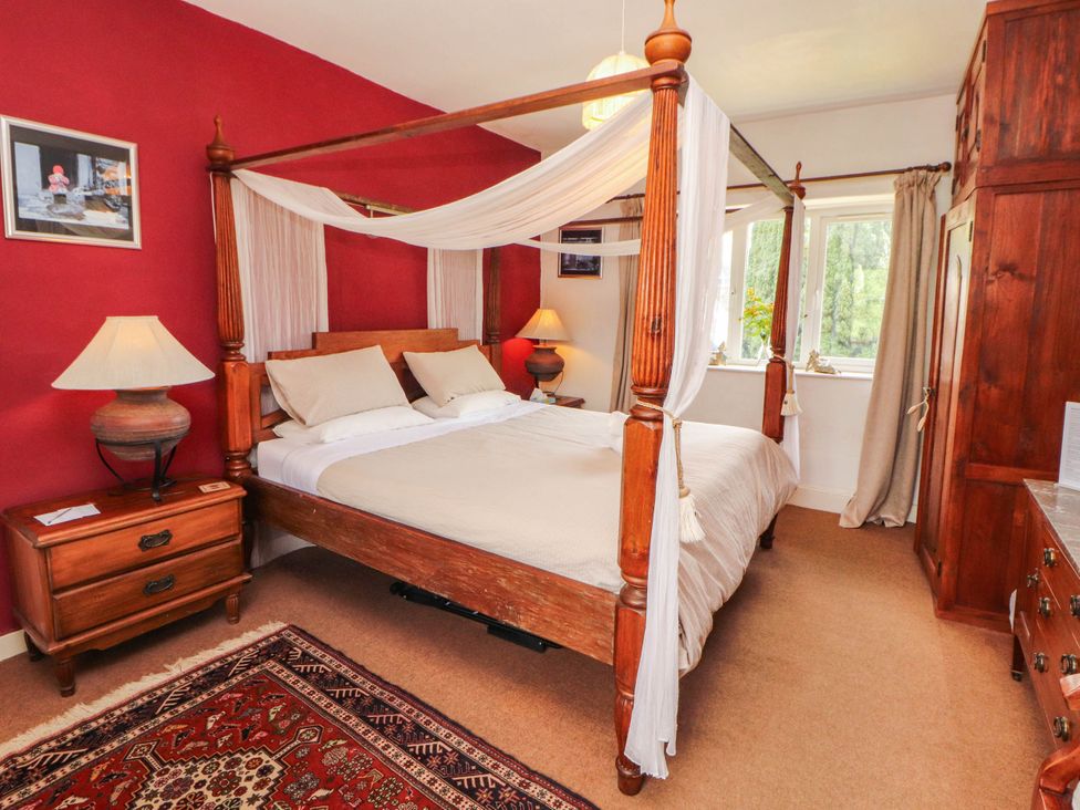 A bedroom with a four-poster bed and bedside table at The School House in Penrith