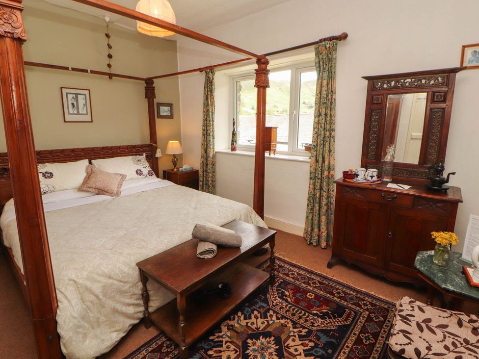 A bedroom with a four-poster bed and a wooden table at The School House in Penrith