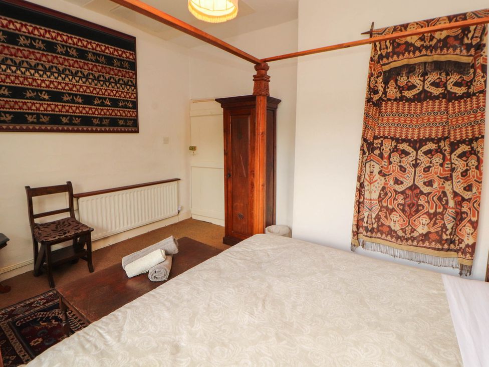 A bedroom with a bed and wall hanging at The School House in Penrith