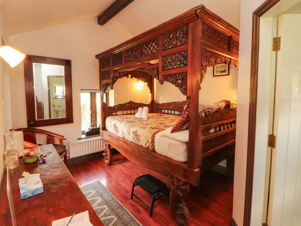 A bedroom with a carved wooden bed and a table at The School House in Penrith