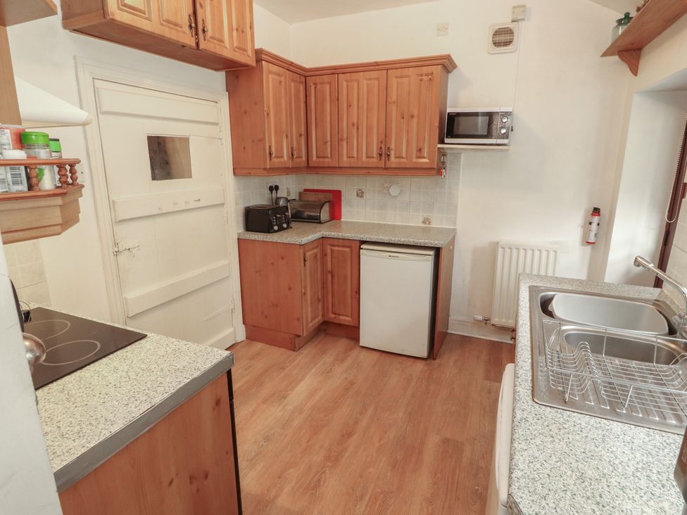 A kitchen with wooden cabinets and appliances at The School House in Patterdale near Glenridding