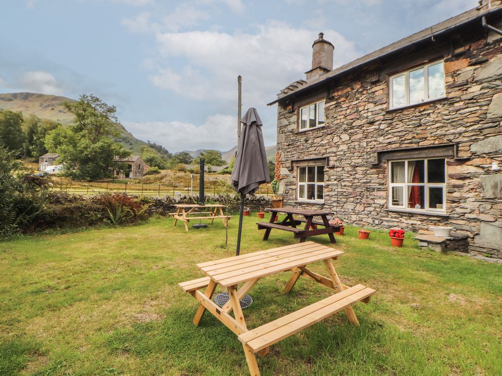 A garden with picnic tables and an umbrella at The School House in Patterdale near Glenridding