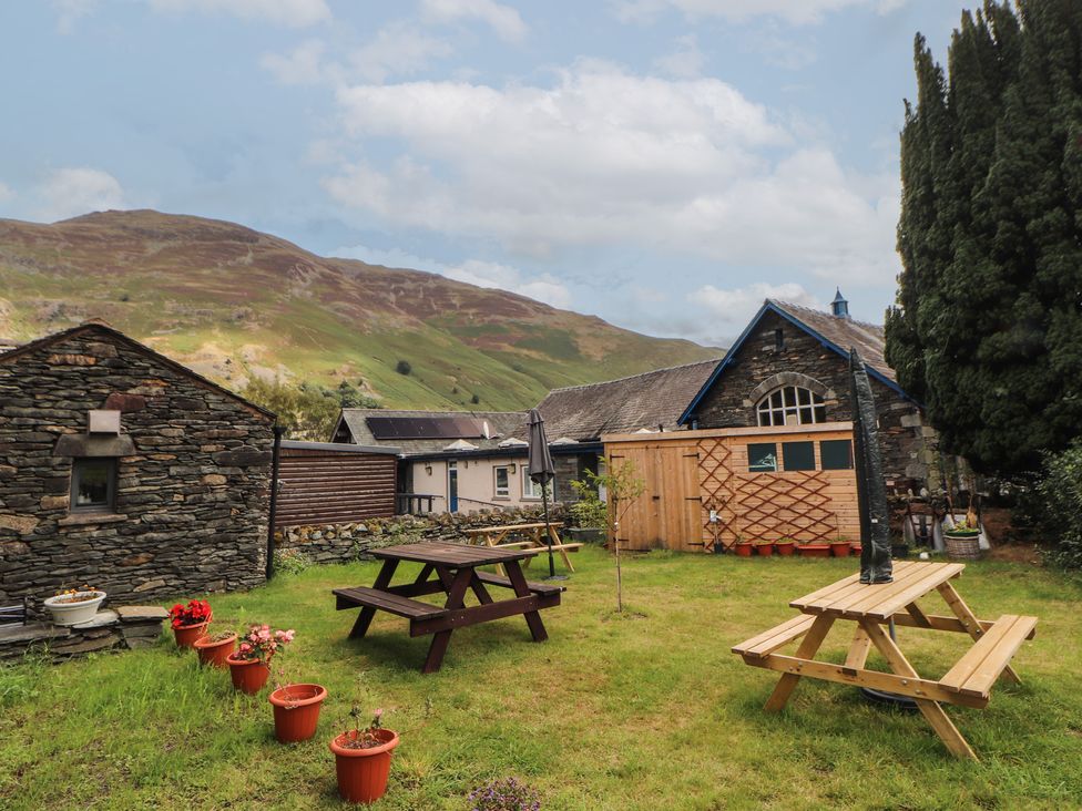 A garden with a stone shed and wooden building at The School House in Patterdale near Glenridding