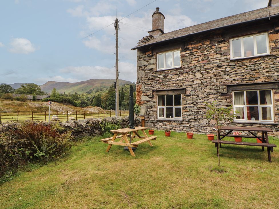 A garden with picnic tables near a stone house at The School House in Patterdale near Glenridding