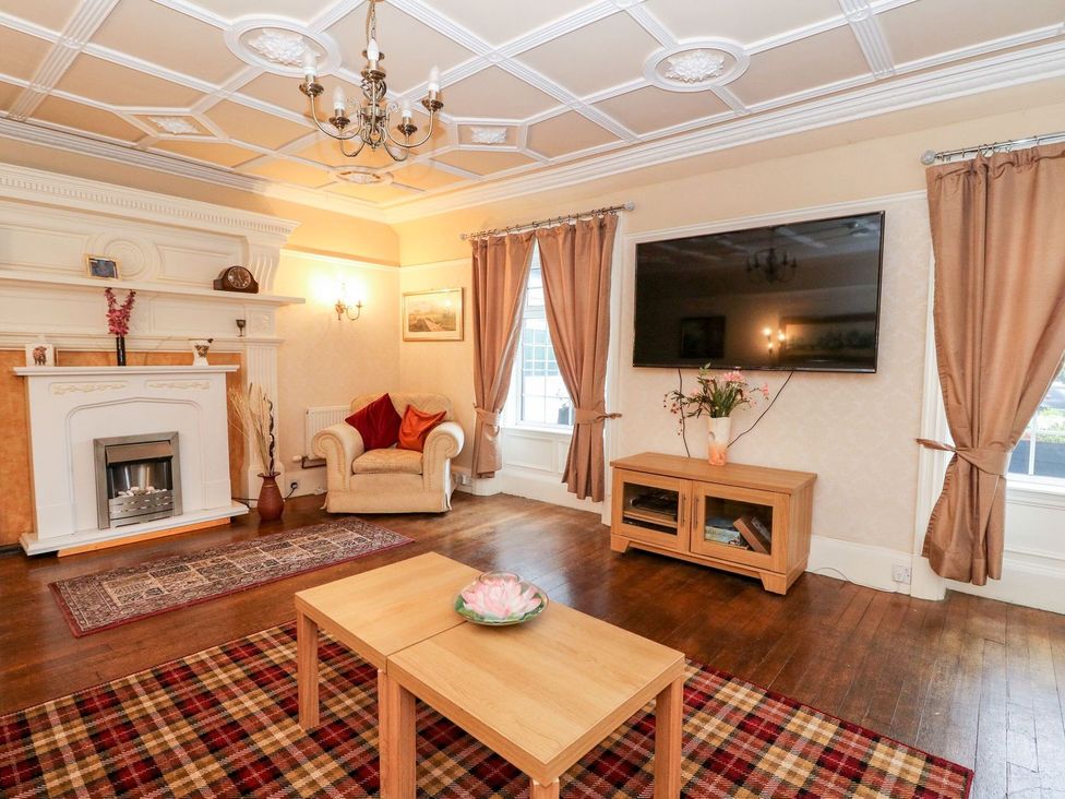A living room with a fireplace, sofa, and television at Seaview Wellness Retreat Carnoustie