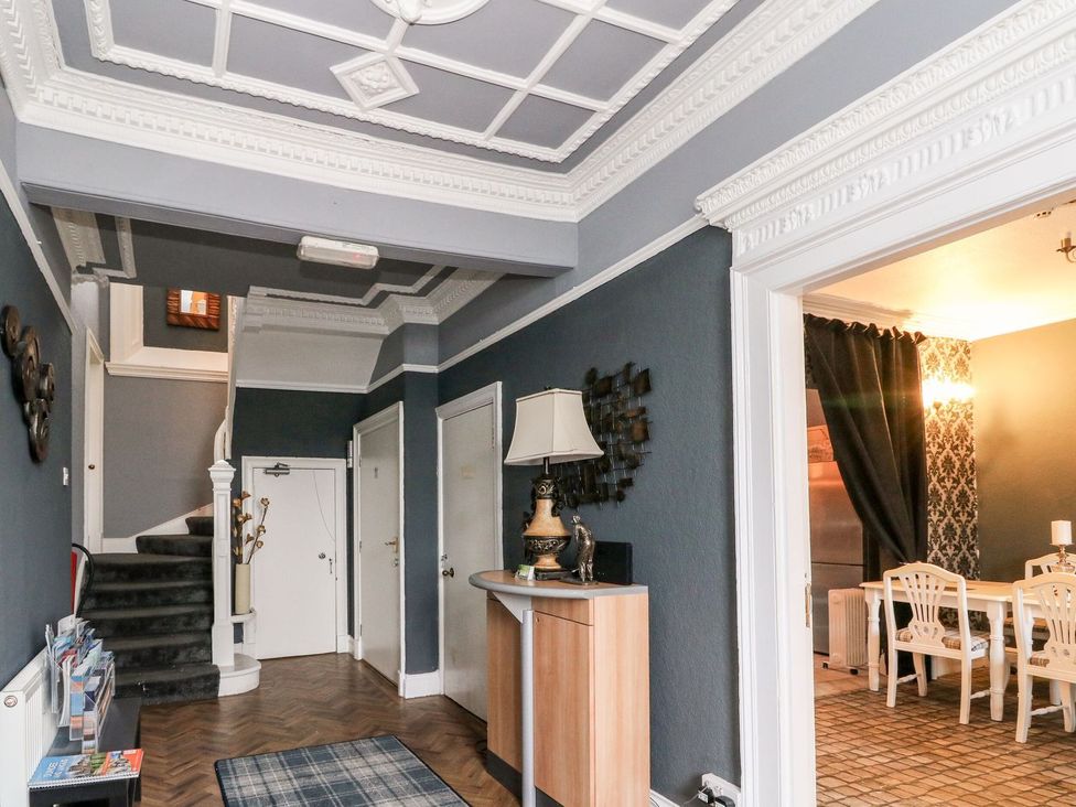 A hallway with a staircase, lamp, and console table at Seaview Wellness Retreat in Carnoustie