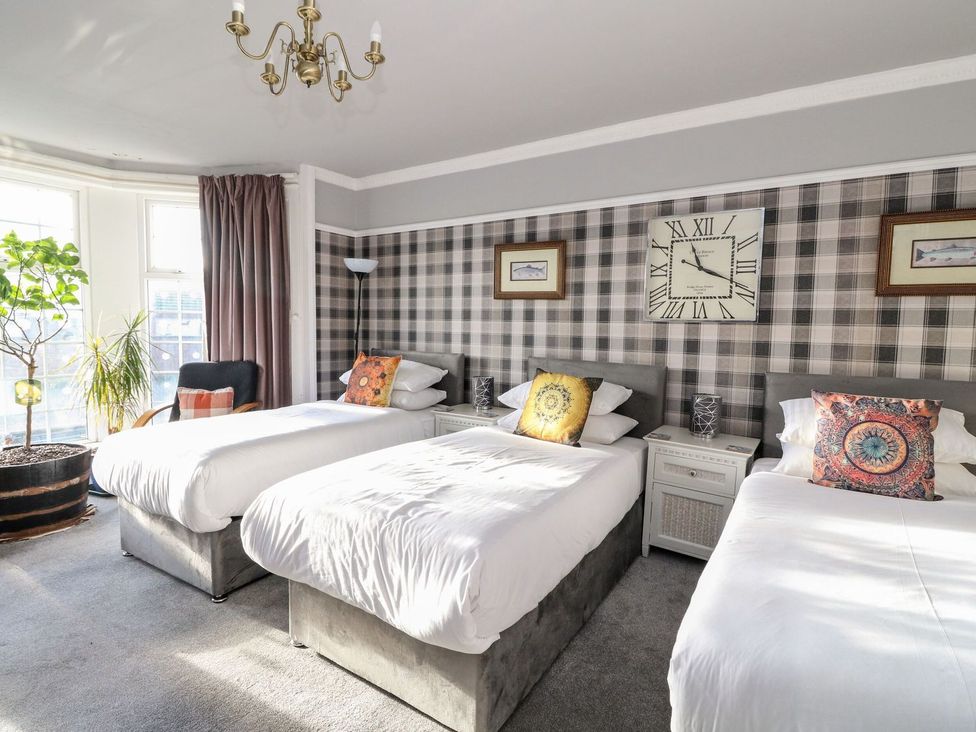 A bedroom with three beds and a plant at Seaview Wellness Retreat Carnoustie