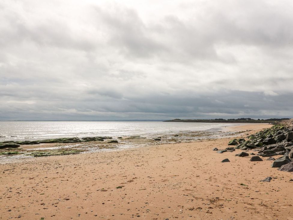A beach with sand and rocks near the ocean at Seaview Wellness Retreat in Carnoustie