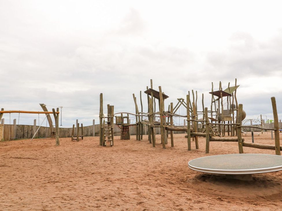 A playground with wooden structures and swings at Seaview Wellness Retreat in Carnoustie