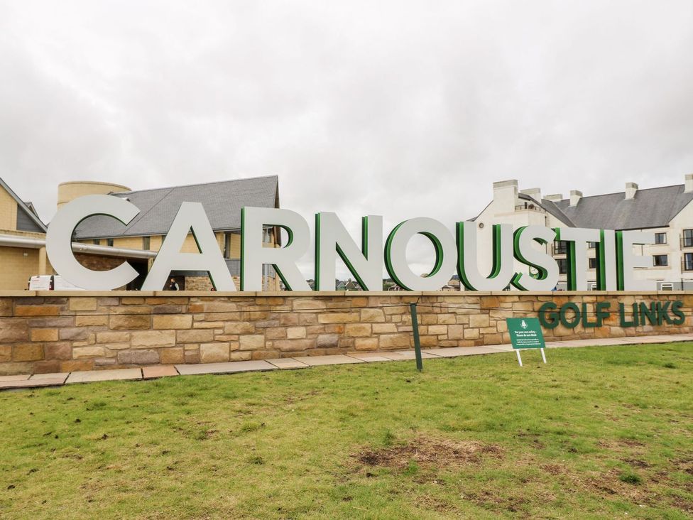 A sign for Carnoustie Golf Links with buildings in the background at Seaview Wellness Retreat in Carnoustie