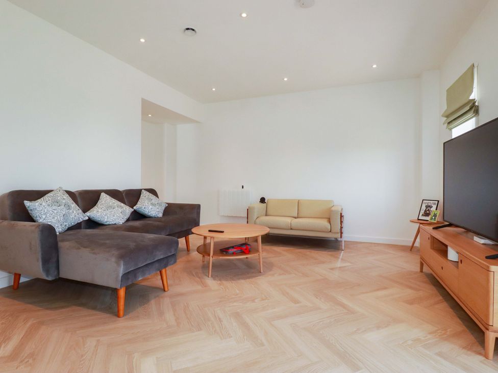 A living room with a sofa and television at Edens in Penwithick