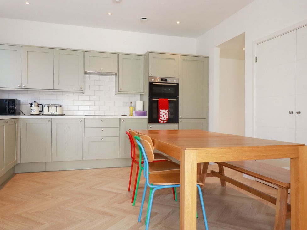 A kitchen with cabinets and a table at Edens in Penwithick