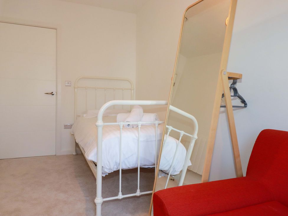 A bedroom with a bed and chair at Edens in Penwithick