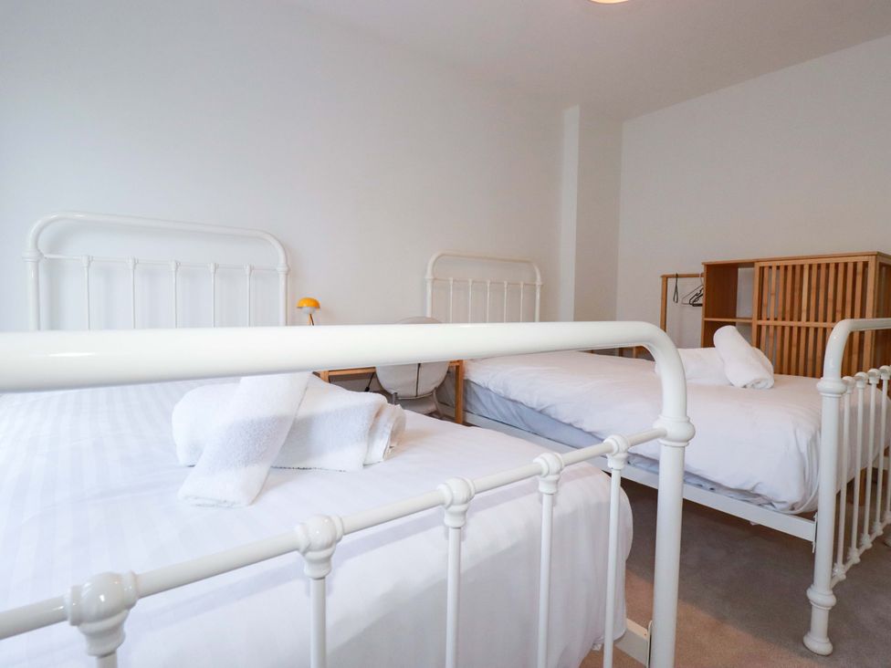 A bedroom with two beds and a wardrobe at Edens in Penwithick