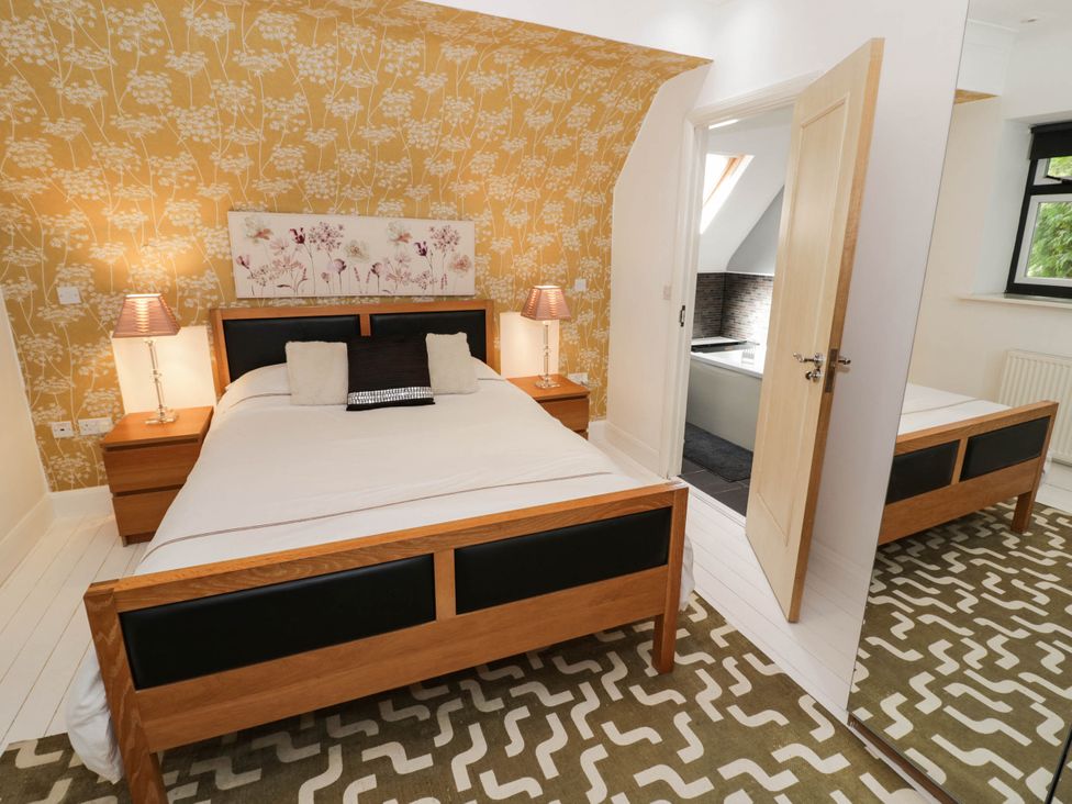 A bedroom with a bed and mirror at Tudor Lodge in Birmingham