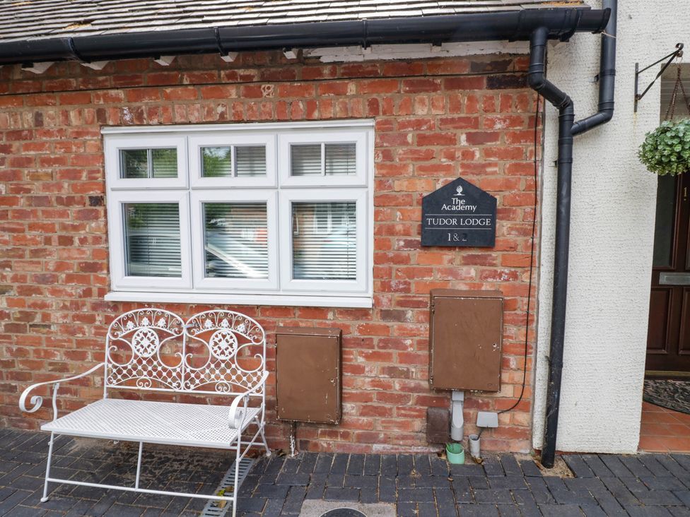 An outdoor view of Tudor Lodge with a bench and a nameplate in Birmingham