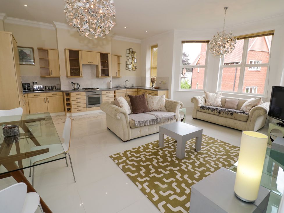 A living room with a sofa and kitchen area at Manor House in Birmingham