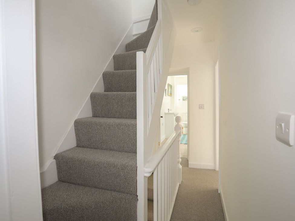 A hallway with carpeted stairs leading to a bathroom at Bodefi in Pwllheli