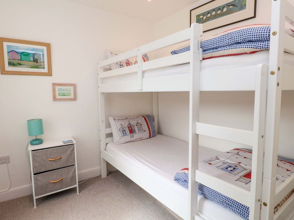 A bedroom with a bunk bed and nightstand at Bodefi in Pwllheli