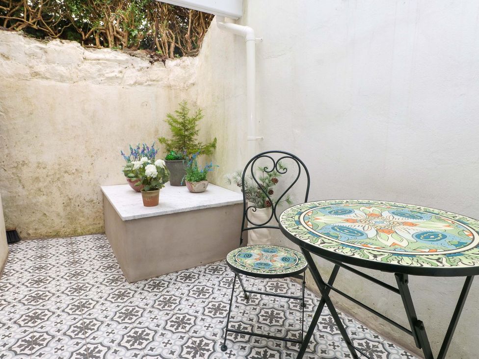 An outdoor area with a table and chair beside planters at Bodefi in Pwllheli