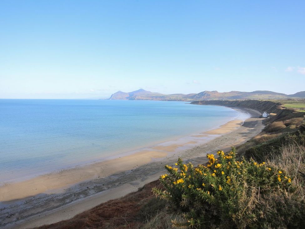 A beach with a view of the ocean and hills at Bodefi in Pwllheli