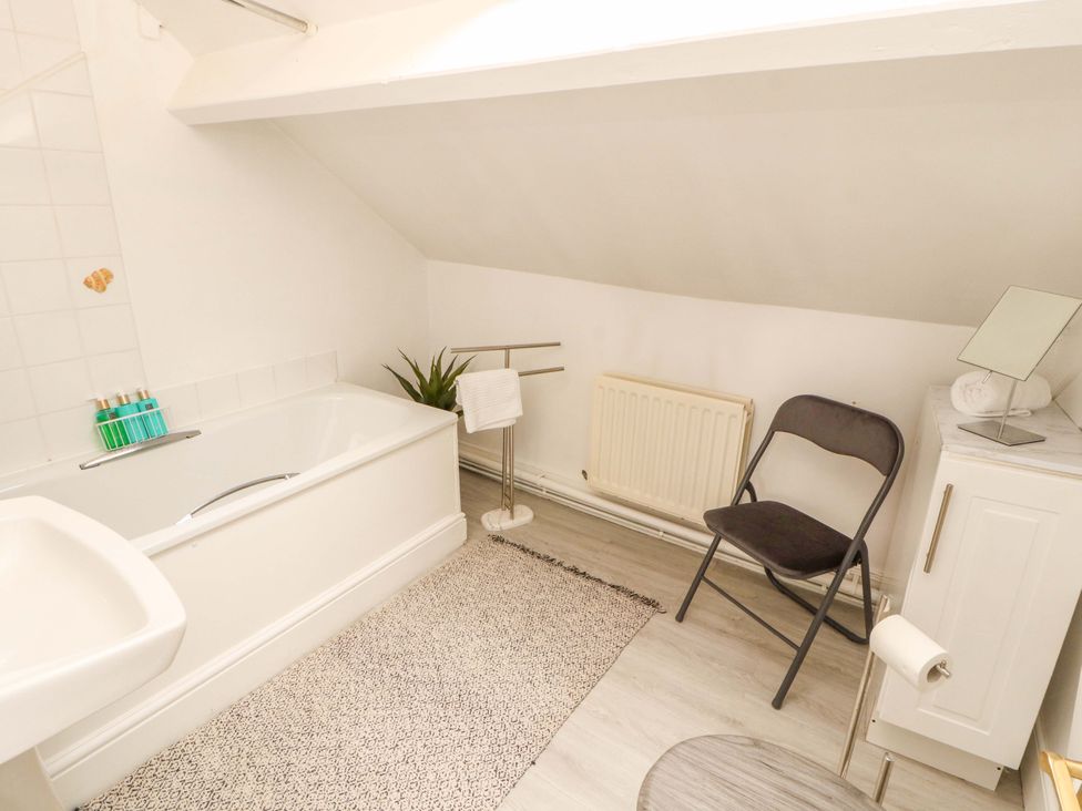 A bathroom with a bathtub and a chair at The Loft Apartment @ The Stag Inn, Maryport