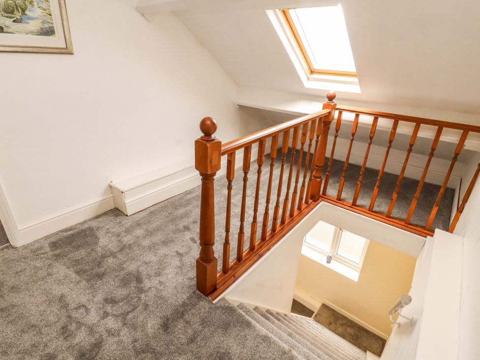 A staircase with a wooden railing and carpeted floor at The Loft Apartment @ The Stag Inn Maryport