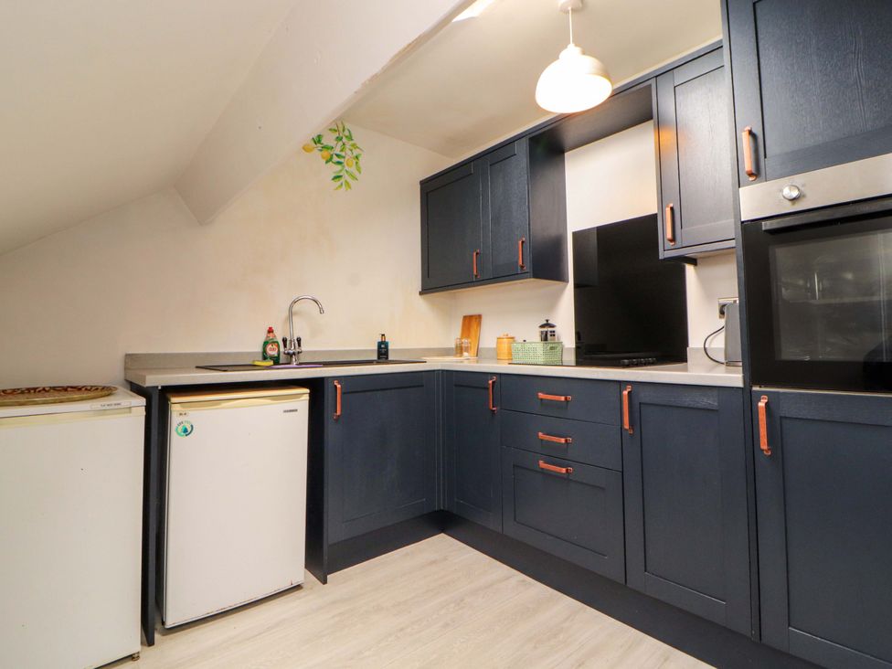 A kitchen with dark cabinets and appliances at The Loft Apartment @ The Stag Inn in Maryport