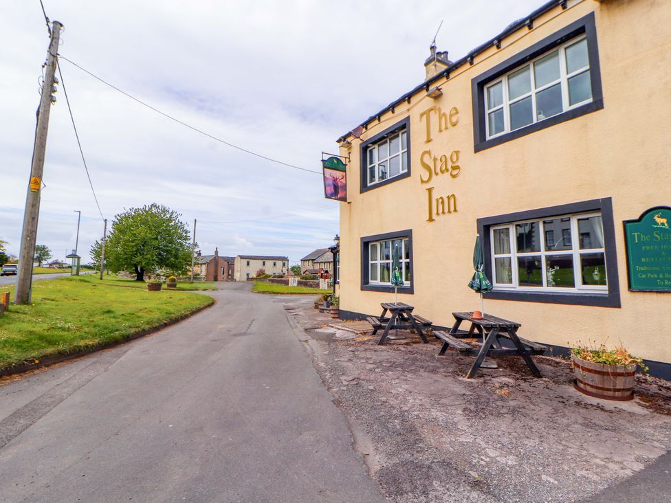 An outdoor view of The Stag Inn with a road and greenery in Maryport