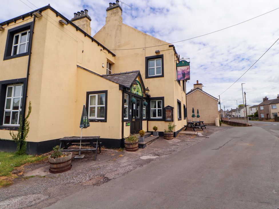 An exterior view of a pub with tables and planters at The Loft Apartment @ The Stag Inn in Maryport