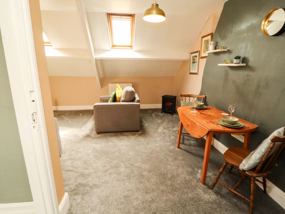 A living room with a sofa, table, and chairs at The Loft Apartment @ The Stag Inn in Maryport