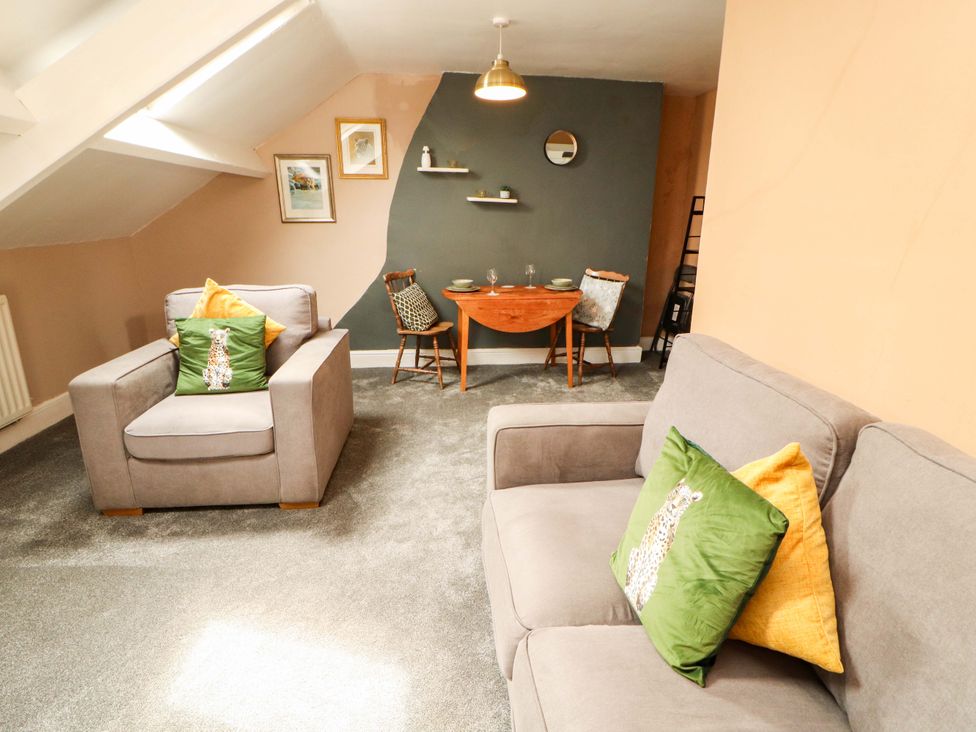 A living room with a couch, armchair, and dining table at The Loft Apartment @ The Stag Inn Maryport