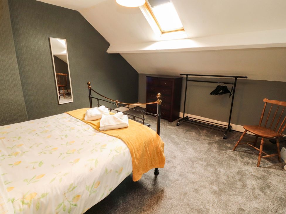 A bedroom with a bed and a hanging clothes rack at The Loft Apartment @ The Stag Inn Maryport
