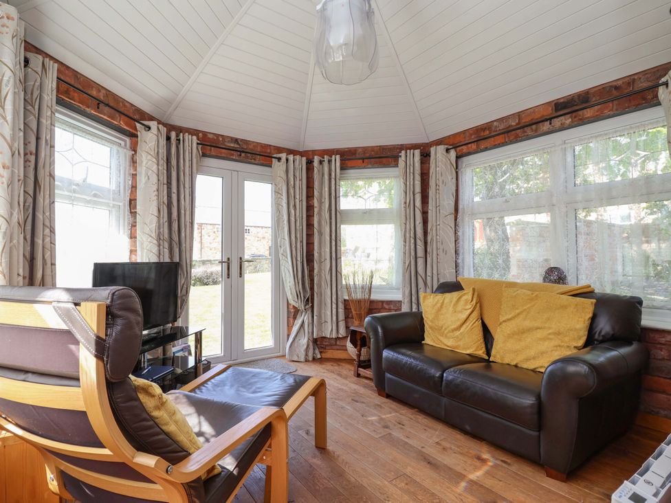 A conservatory with a sofa and armchair at Ty Haf in Rhosemor