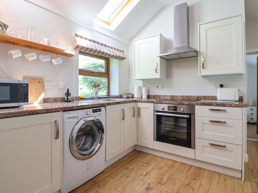 A kitchen with appliances including a washing machine and microwave at Ty Haf in Rhosemor
