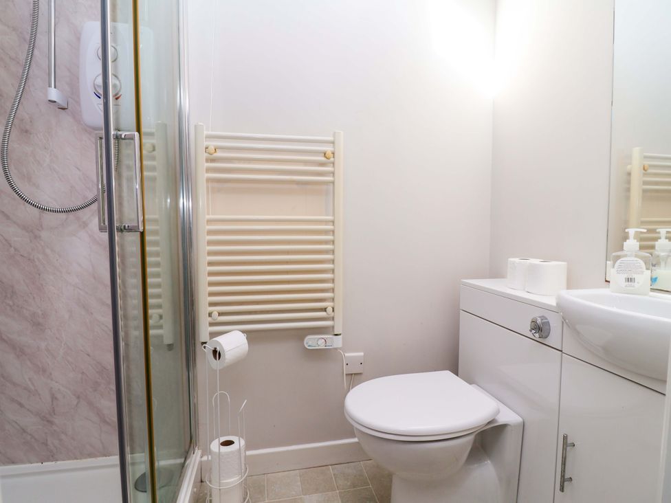 A bathroom with a shower, toilet, sink, and towel radiator at Ty Haf in Rhosemor