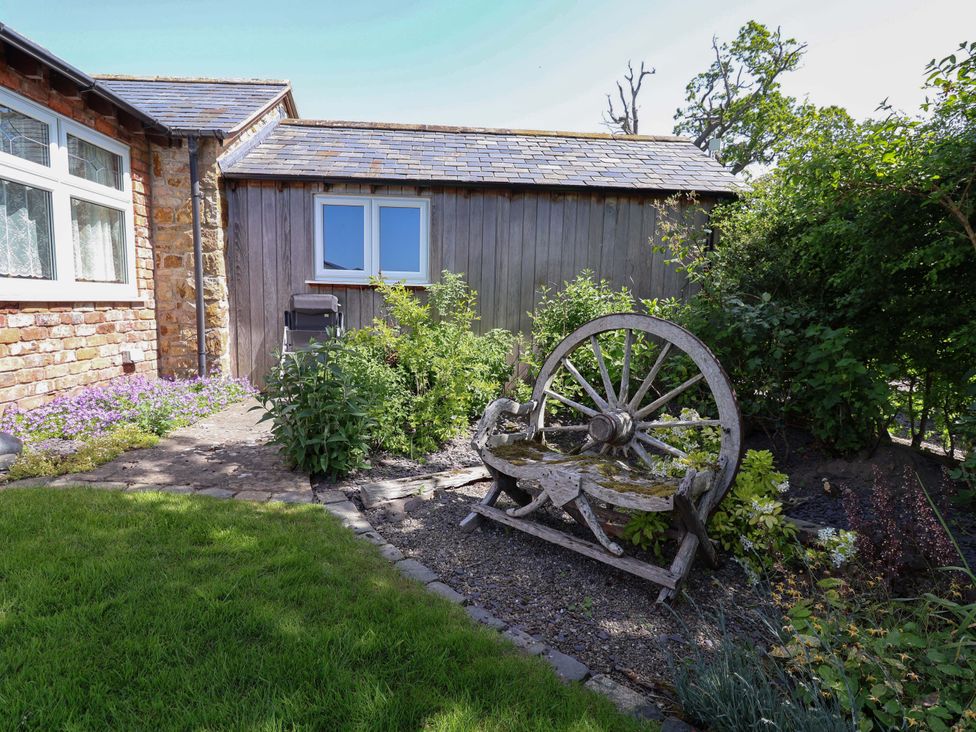A garden with a wooden wheel feature at Ty Haf Rhosemor