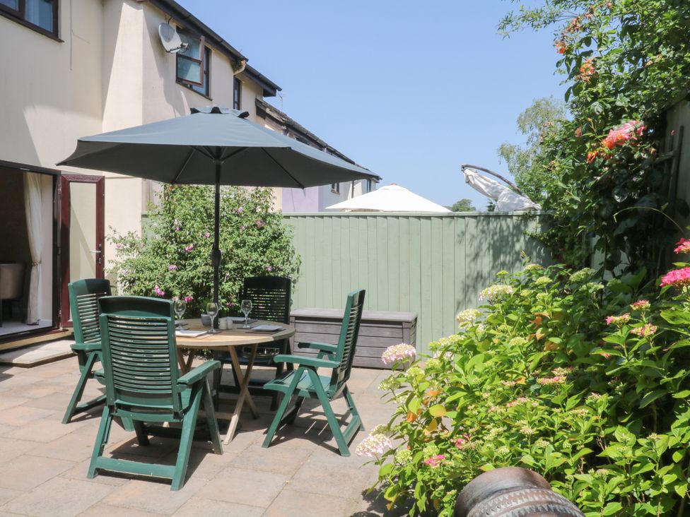 A garden with a table and chairs under an umbrella at Marldon Mews in Marldon