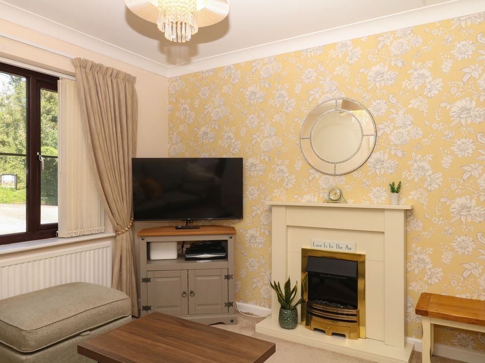 A living room with a TV, seating area, and fireplace at Marldon Mews in Marldon