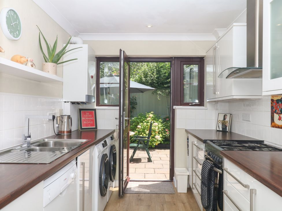 A kitchen with appliances and open door leading to garden at Marldon Mews in Marldon
