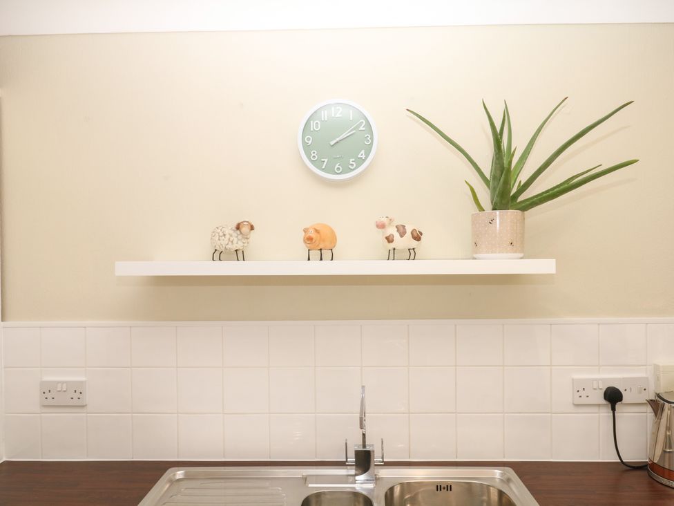 A kitchen with a clock and figurines on a shelf at Marldon Mews in Marldon