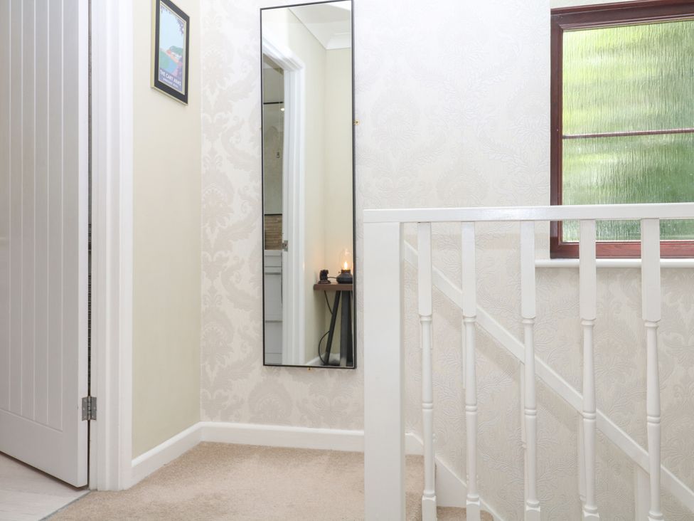 A hallway with a mirror and stair railing at Marldon Mews in Marldon