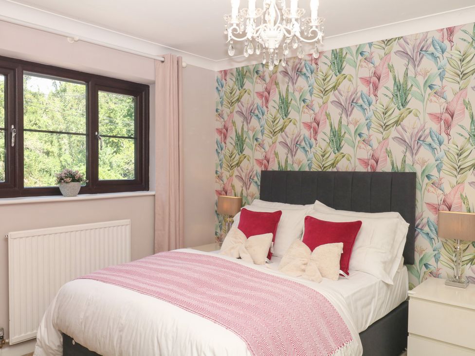 A bedroom with a bed and floral wallpaper at Marldon Mews in Marldon