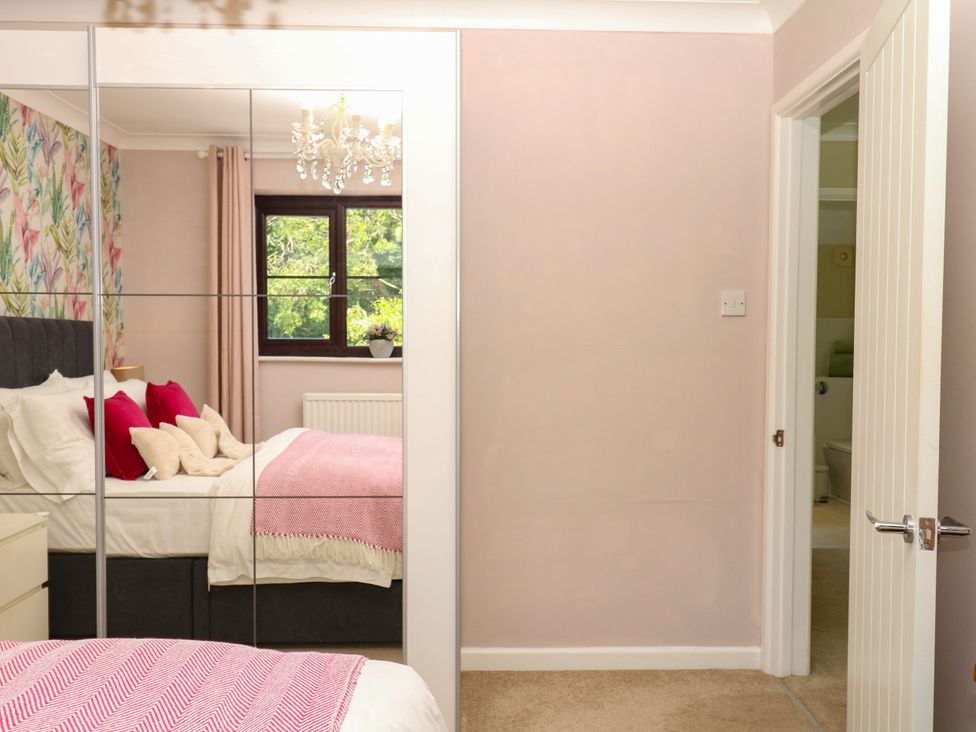 A bedroom with a bed and a mirror at Marldon Mews in Marldon