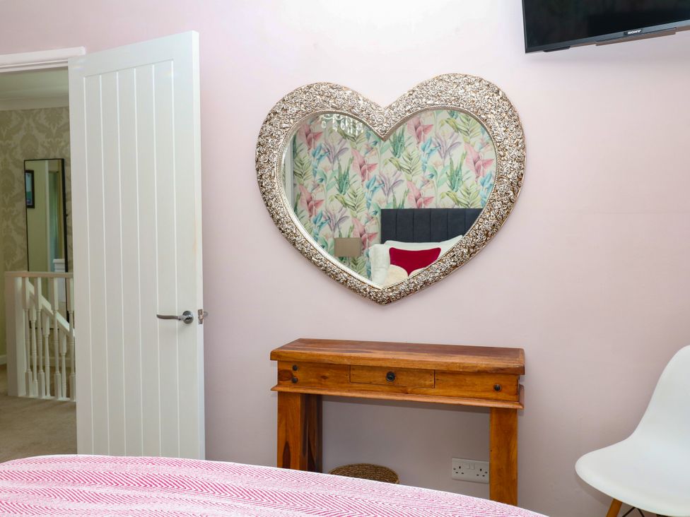 A bedroom with a heart-shaped mirror and a wooden table at Marldon Mews in Marldon