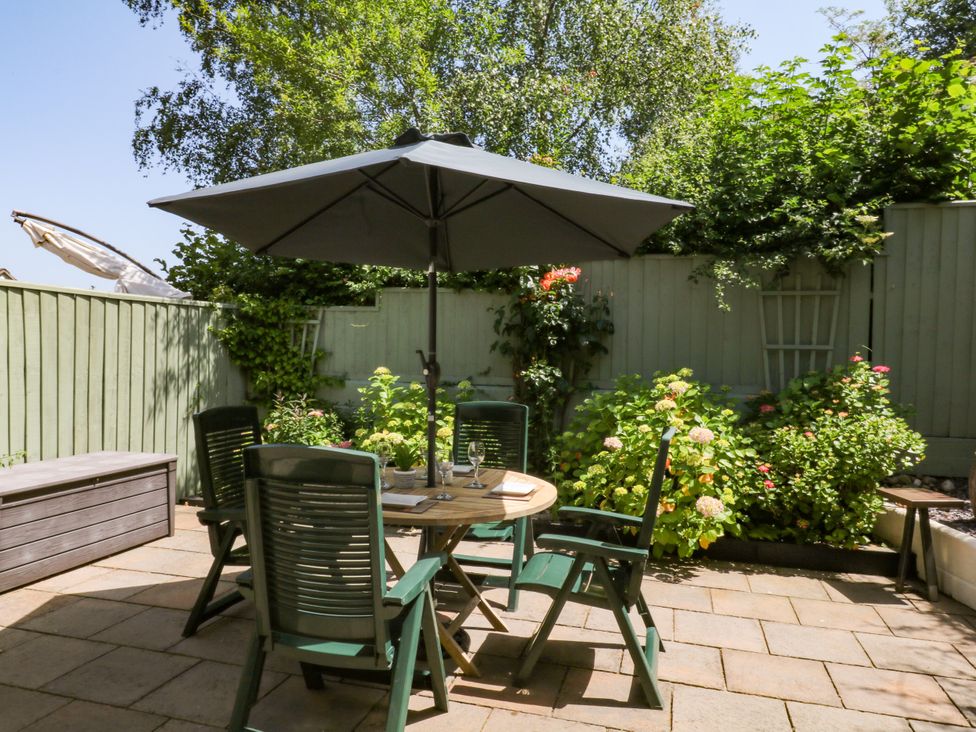 A garden with a table and chairs under an umbrella at Marldon Mews in Marldon