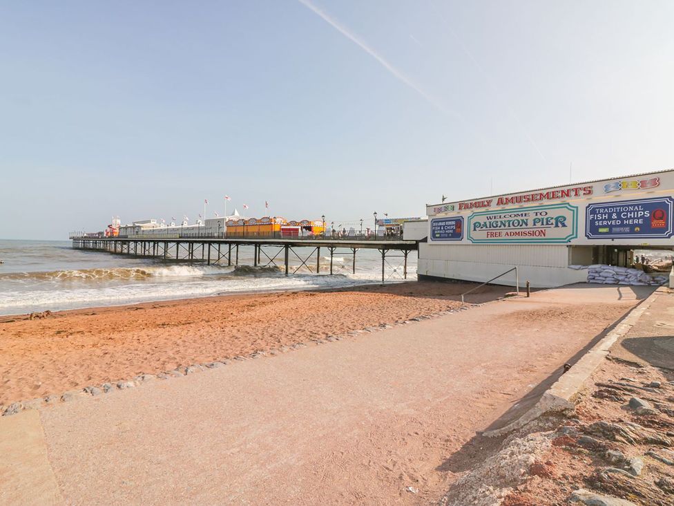 A pier with amusement signs and waves at Paignton Pier in Paignton