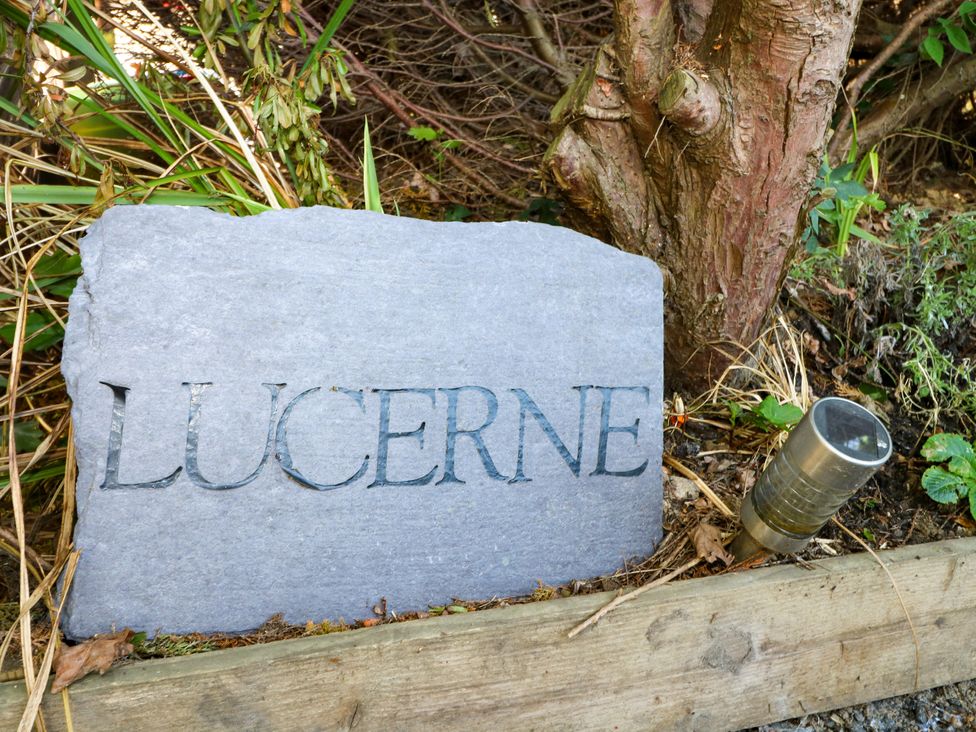 A stone sign with the name Lucerne and a garden light at Lucerne Cottage in Dorking