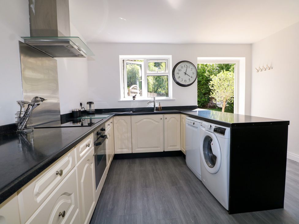 A kitchen with a washing machine and black countertops at Lucerne Cottage in Dorking