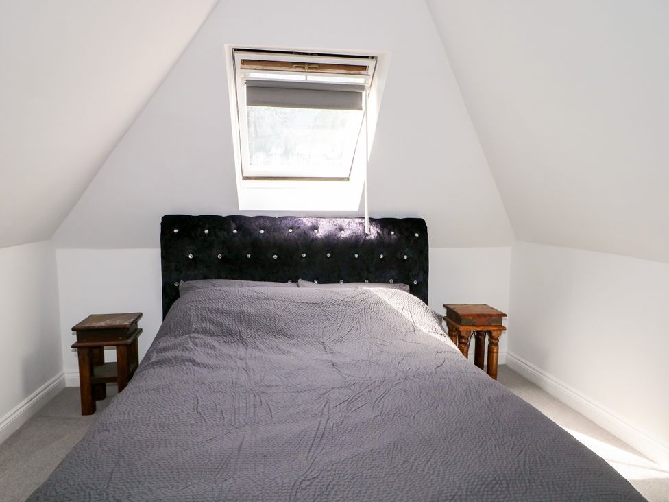 A bedroom with a bed and bedside tables at Lucerne Cottage, Dorking